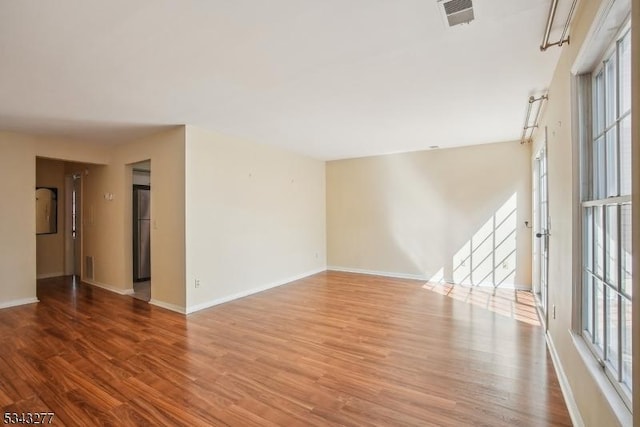 spare room featuring visible vents, baseboards, and wood finished floors