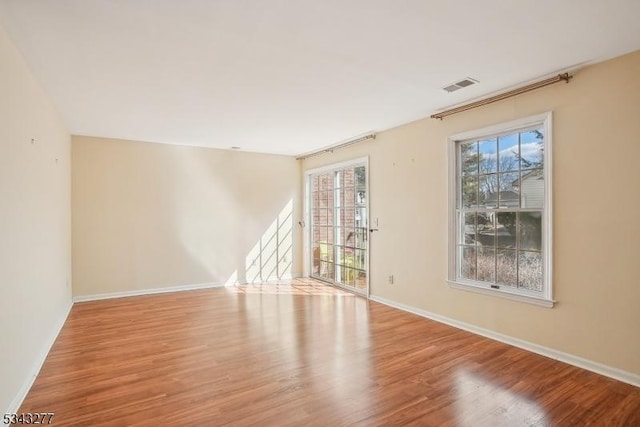 spare room with visible vents, a healthy amount of sunlight, and wood finished floors