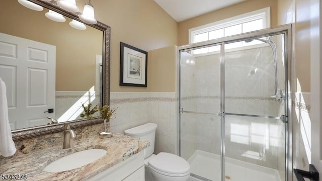 full bath with a wainscoted wall, toilet, a stall shower, tile walls, and vanity