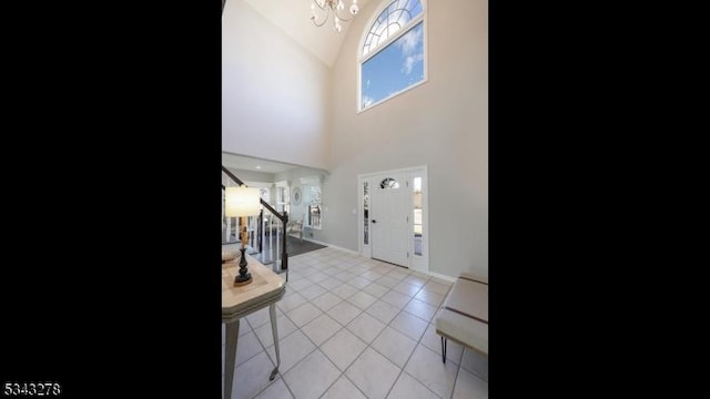 foyer with baseboards, a chandelier, stairway, vaulted ceiling, and light tile patterned flooring