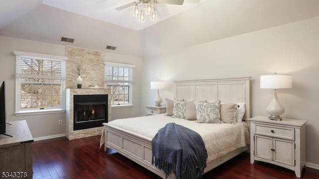 bedroom featuring visible vents, baseboards, lofted ceiling, a fireplace, and dark wood-style flooring