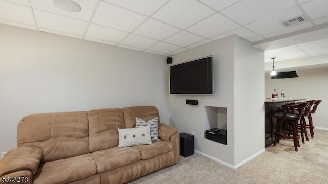 living area with visible vents, a paneled ceiling, carpet, and a dry bar