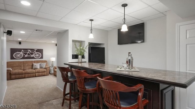 bar featuring pendant lighting, black fridge, a drop ceiling, a bar, and carpet