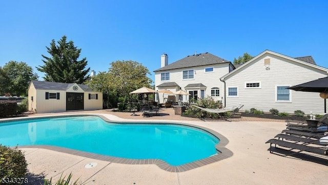 outdoor pool featuring a patio and an outbuilding