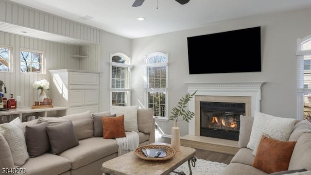 living area featuring a glass covered fireplace, recessed lighting, a ceiling fan, and wood finished floors