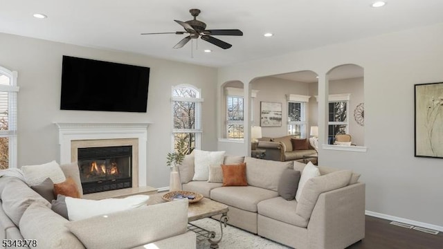 living area featuring visible vents, dark wood-type flooring, baseboards, recessed lighting, and a glass covered fireplace