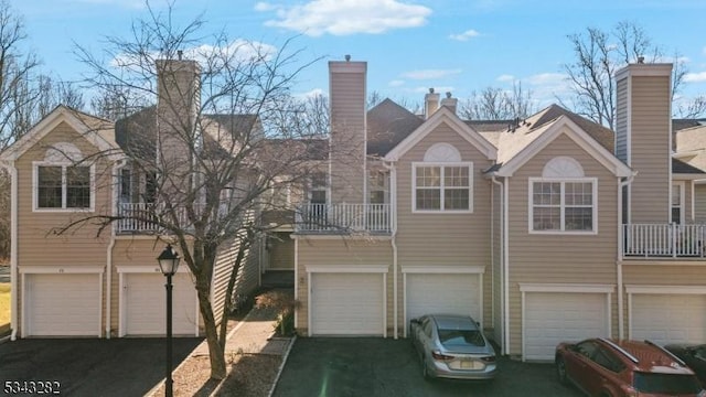 view of property featuring an attached garage, a balcony, and driveway