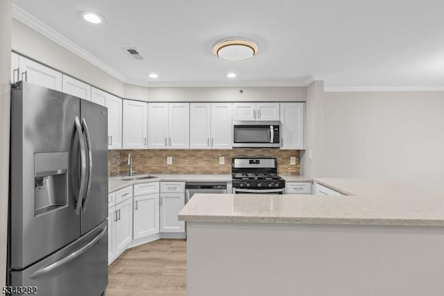 kitchen with visible vents, a peninsula, a sink, appliances with stainless steel finishes, and white cabinetry