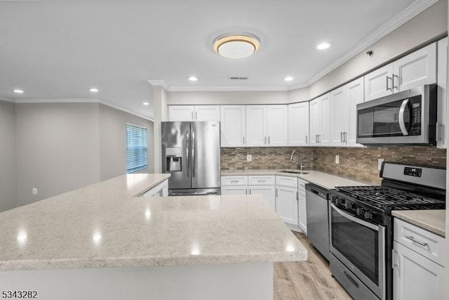 kitchen with light stone counters, a sink, decorative backsplash, stainless steel appliances, and white cabinetry