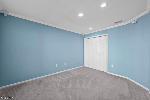 unfurnished bedroom with visible vents, crown molding, baseboards, carpet floors, and a closet