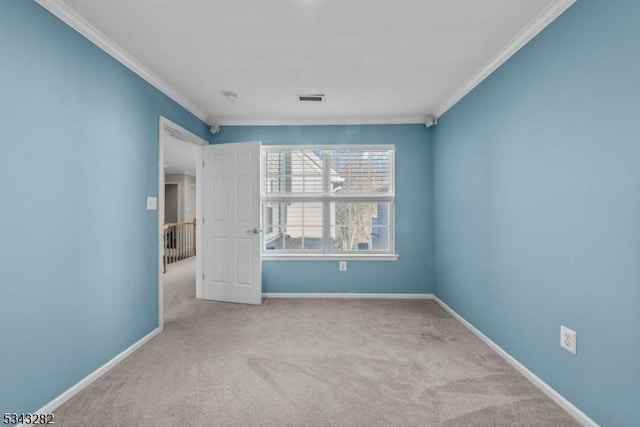 spare room with crown molding, baseboards, and visible vents