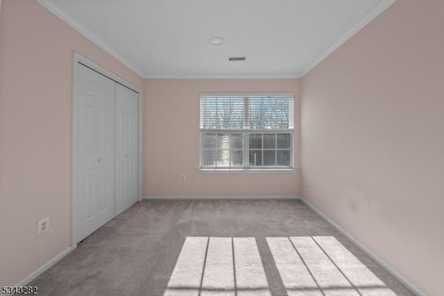 unfurnished bedroom with visible vents, carpet flooring, baseboards, and ornamental molding