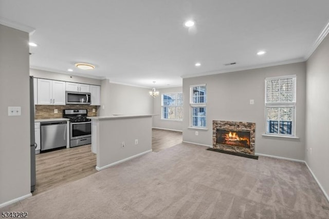 kitchen with backsplash, appliances with stainless steel finishes, white cabinets, a fireplace, and crown molding