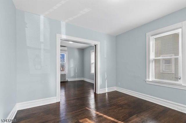 empty room featuring radiator heating unit, wood finished floors, and baseboards