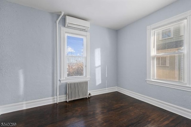 unfurnished room featuring dark wood-style floors, radiator, an AC wall unit, and baseboards