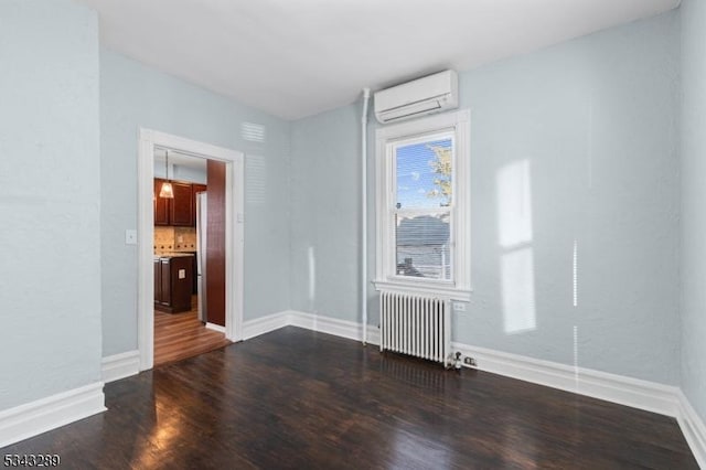 spare room with dark wood finished floors, baseboards, radiator heating unit, and a wall unit AC