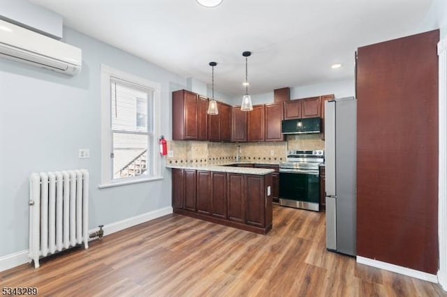 kitchen featuring radiator heating unit, light countertops, a wall mounted air conditioner, appliances with stainless steel finishes, and tasteful backsplash