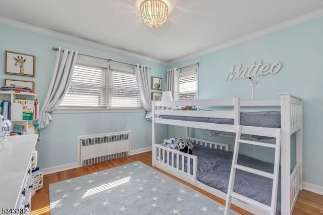 bedroom featuring radiator, wood finished floors, baseboards, and ornamental molding