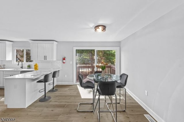 dining room featuring visible vents, baseboards, and light wood finished floors