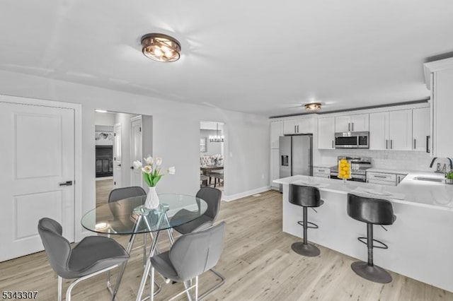 kitchen featuring a sink, stainless steel appliances, light wood finished floors, a chandelier, and light countertops