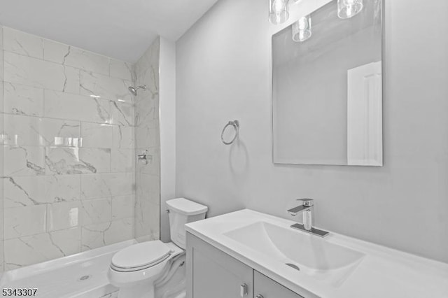 bathroom featuring vanity, toilet, and a tile shower