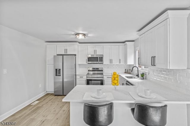 kitchen with a sink, stainless steel appliances, backsplash, and a peninsula