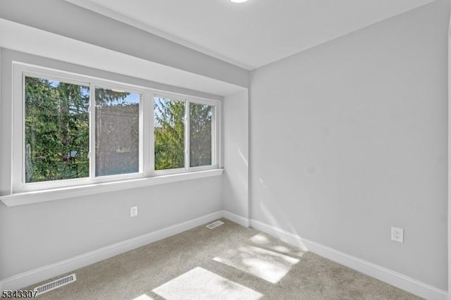 empty room featuring visible vents, baseboards, and carpet flooring