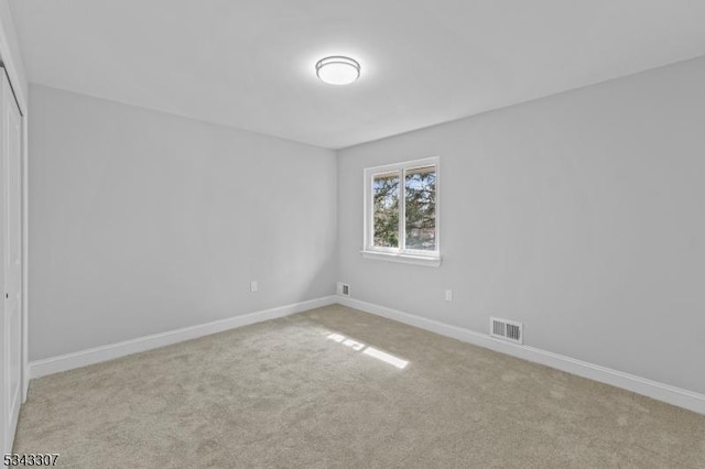 empty room with visible vents, baseboards, and light colored carpet