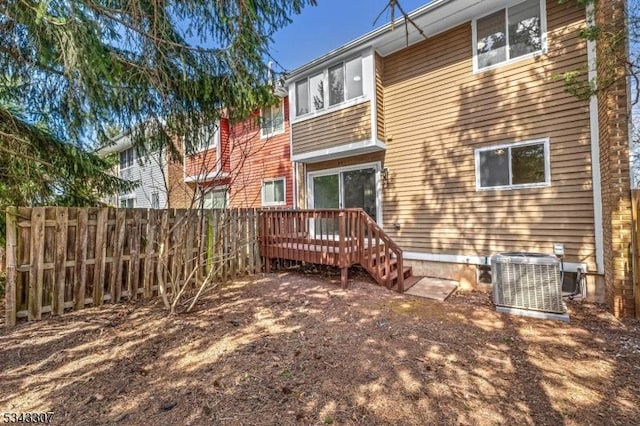 rear view of property featuring central air condition unit, fence, and a wooden deck