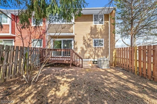 rear view of house with cooling unit, a deck, and a fenced backyard