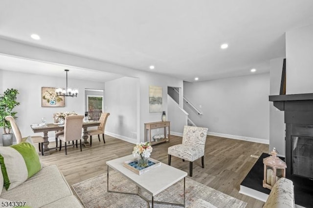 living room with wood finished floors, baseboards, recessed lighting, stairs, and a glass covered fireplace