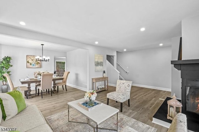 living area featuring a glass covered fireplace, wood finished floors, and recessed lighting