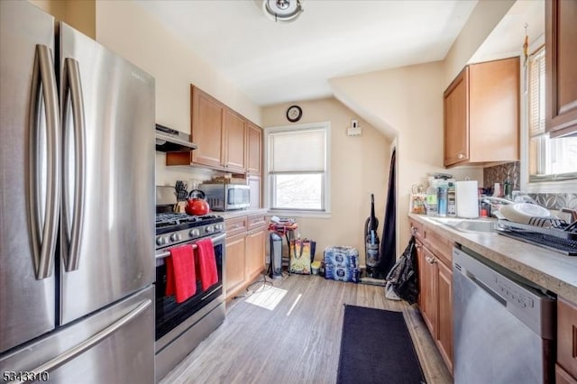 kitchen with under cabinet range hood, a healthy amount of sunlight, appliances with stainless steel finishes, and light countertops