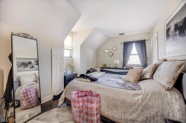 bedroom with vaulted ceiling, wood finished floors, and visible vents