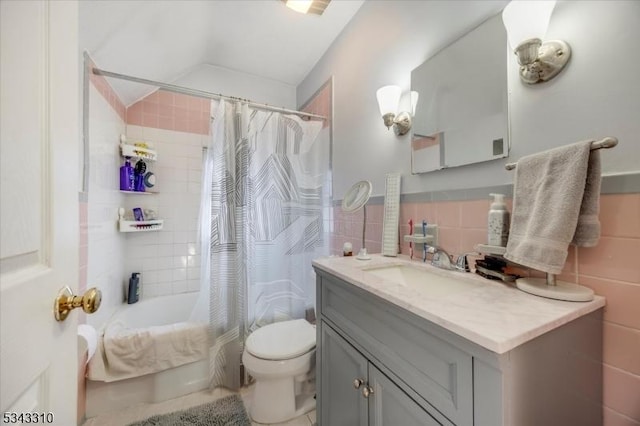 full bath with toilet, vanity, vaulted ceiling, shower / tub combo, and tile walls