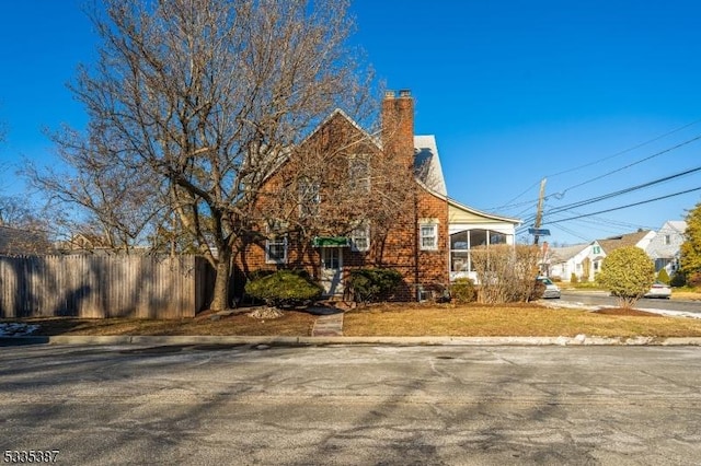 view of property exterior featuring a yard, fence, brick siding, and a chimney