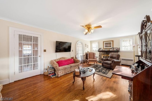 living room with radiator, wood finished floors, a ceiling fan, and ornamental molding