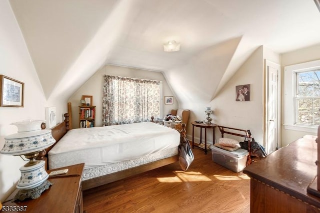 bedroom with lofted ceiling and light wood finished floors