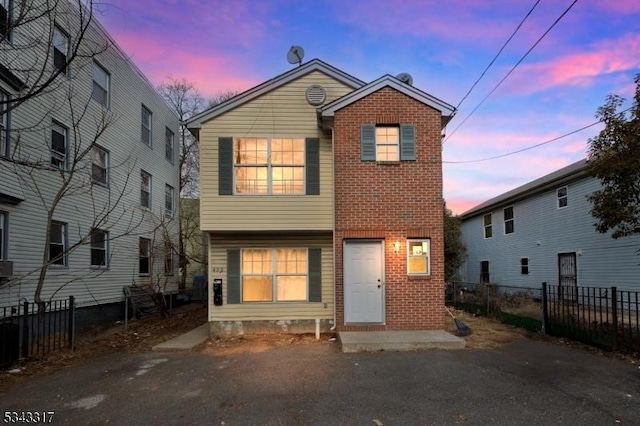 view of front of house featuring brick siding and fence