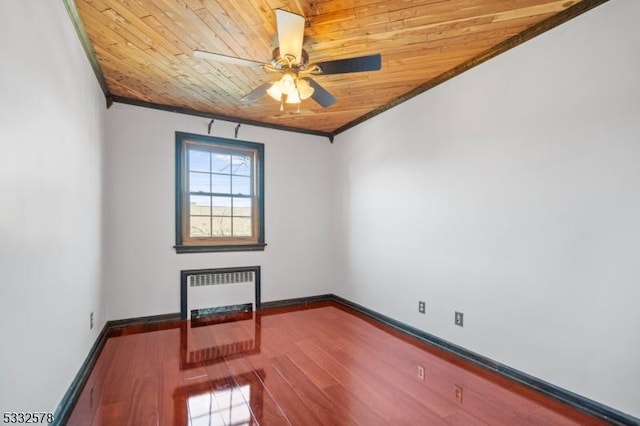 empty room with ornamental molding, wood finished floors, radiator, wooden ceiling, and baseboards