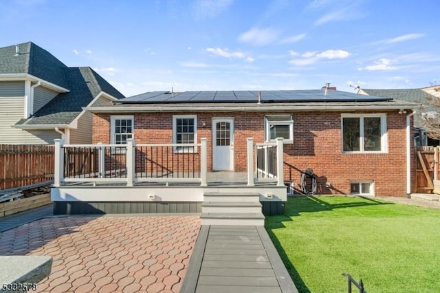 back of property with brick siding, a lawn, and fence