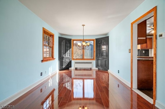 unfurnished dining area featuring wood finished floors, baseboards, and a chandelier