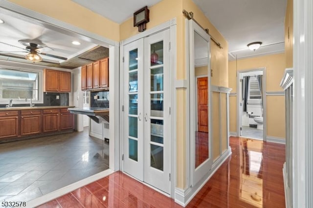 kitchen with a sink, ceiling fan, light countertops, brown cabinets, and backsplash