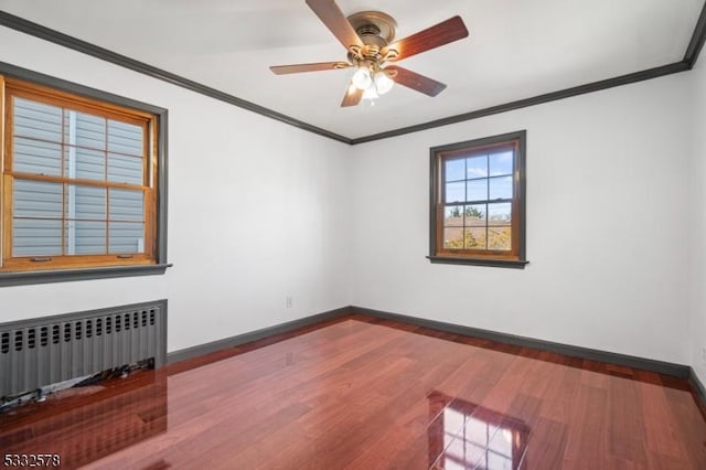 spare room featuring baseboards, radiator, wood finished floors, and ornamental molding