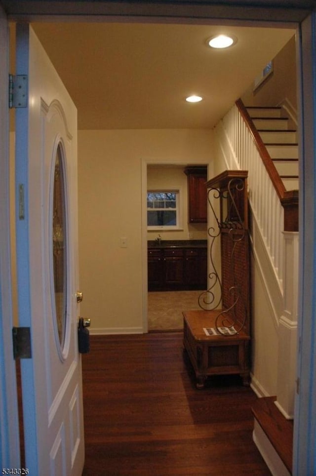 corridor featuring recessed lighting, baseboards, wood finished floors, and stairs