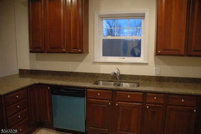 kitchen with a sink, dishwashing machine, and dark stone counters