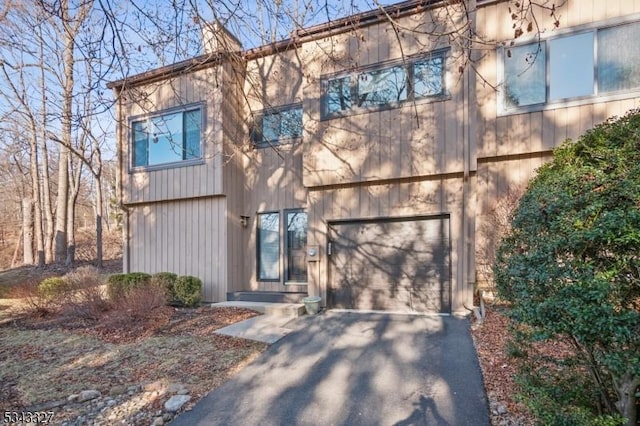 view of front of home featuring an attached garage, a chimney, and driveway