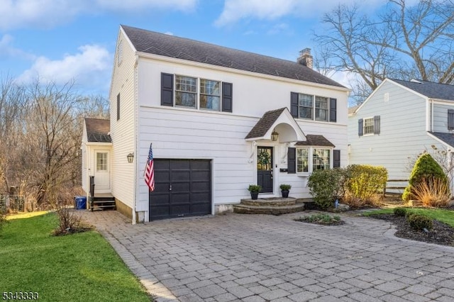 view of front of house with a chimney, decorative driveway, and a garage