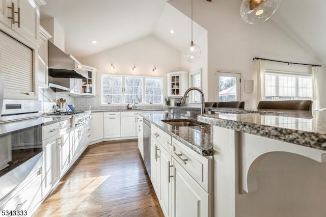 kitchen with light wood-style flooring, a sink, stone countertops, stainless steel dishwasher, and white cabinetry