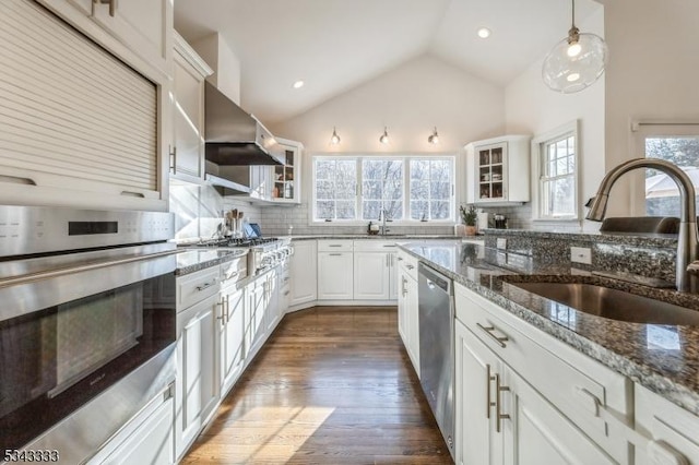 kitchen with tasteful backsplash, glass insert cabinets, vaulted ceiling, appliances with stainless steel finishes, and a sink